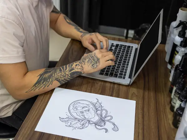 Tatuażysta projektujący tatuaż na laptopie